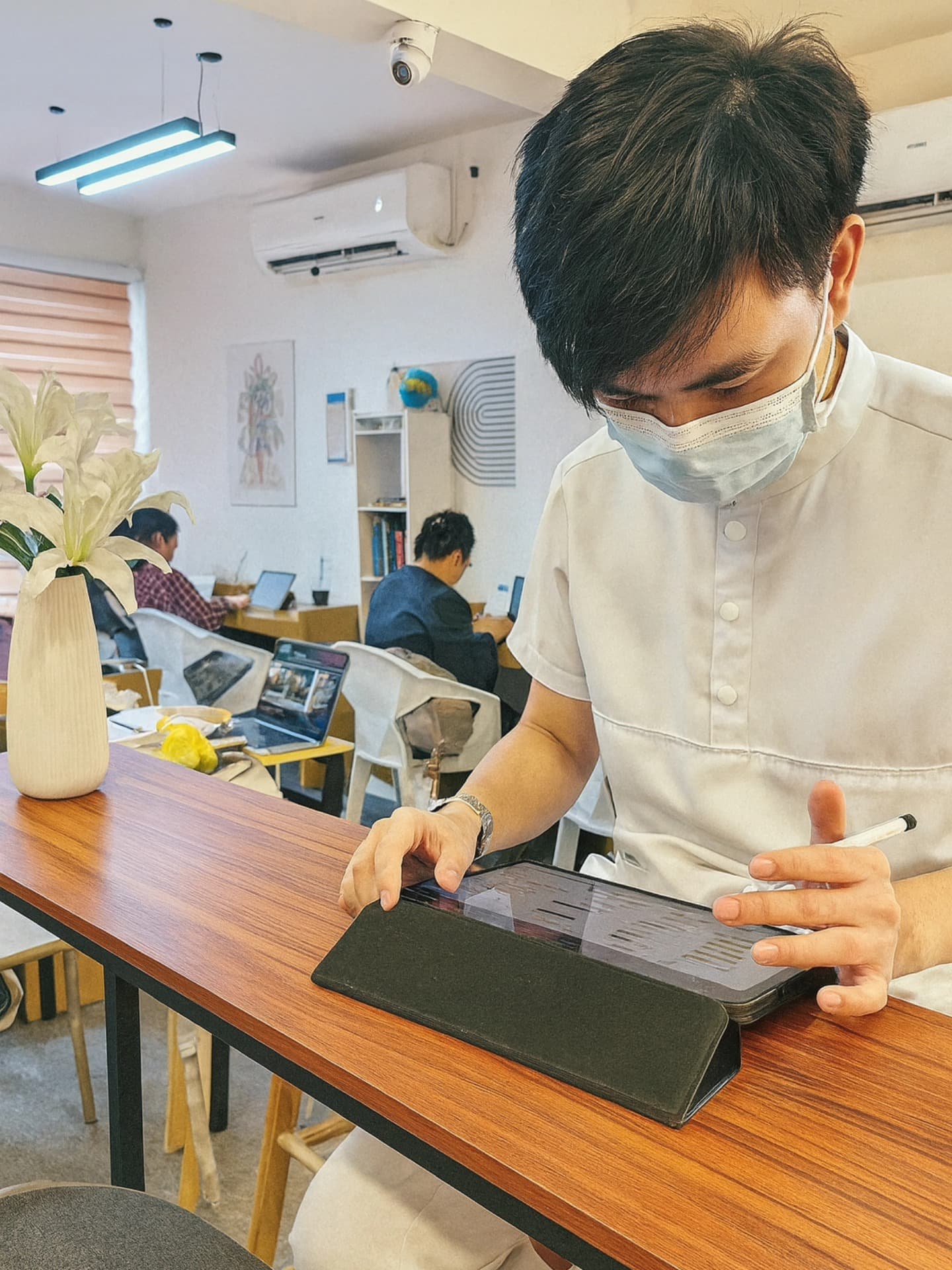 Customer writing on a tablet at WeeCup Call Cafe