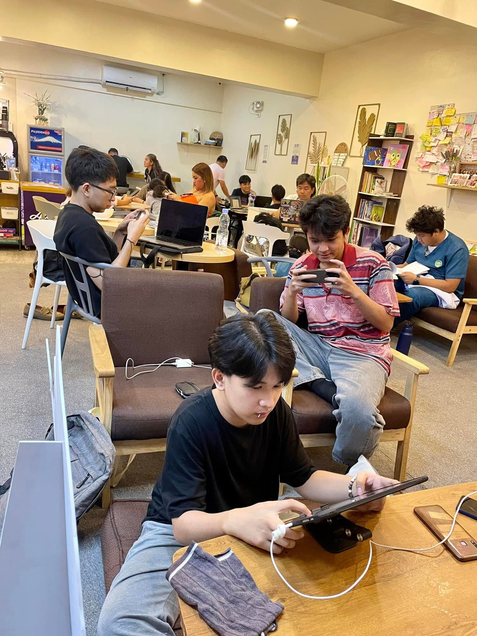 Student using a phone near cafe seating and outlets